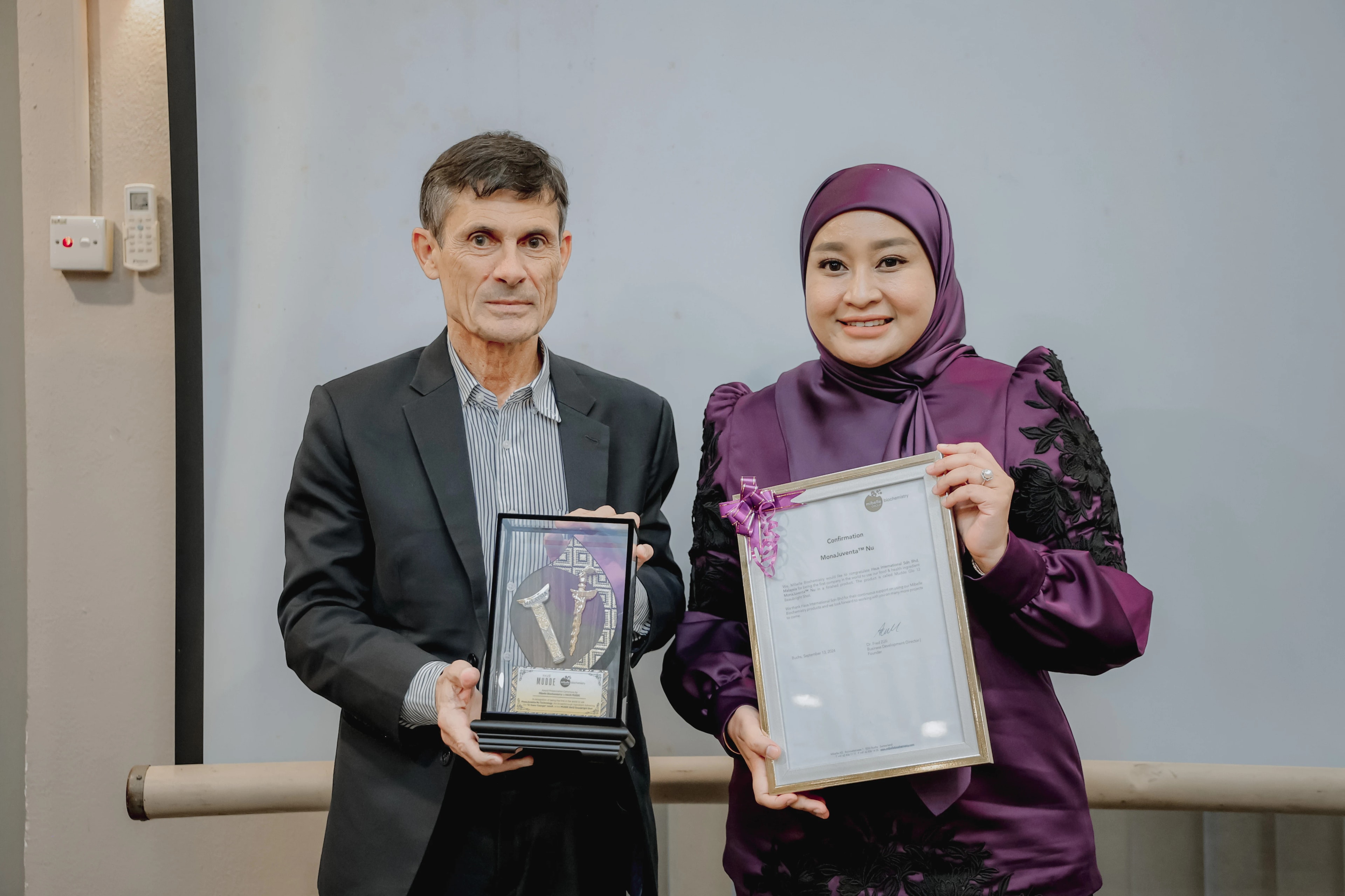 Dr. Fred Zulli and Eiyma Jalil holding the authenticated confirmation deed